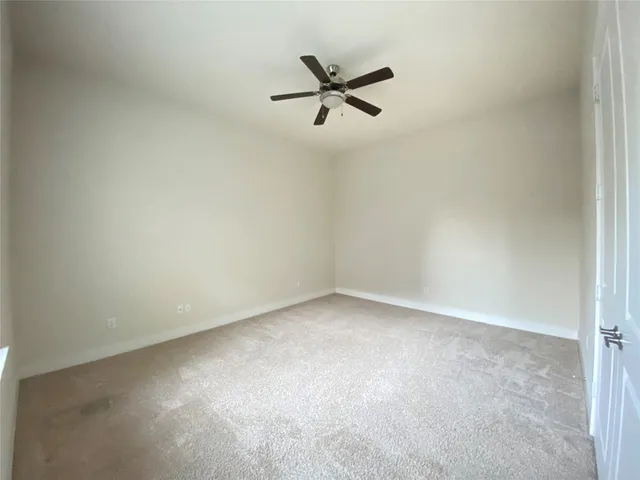 an empty room with a ceiling fan and window