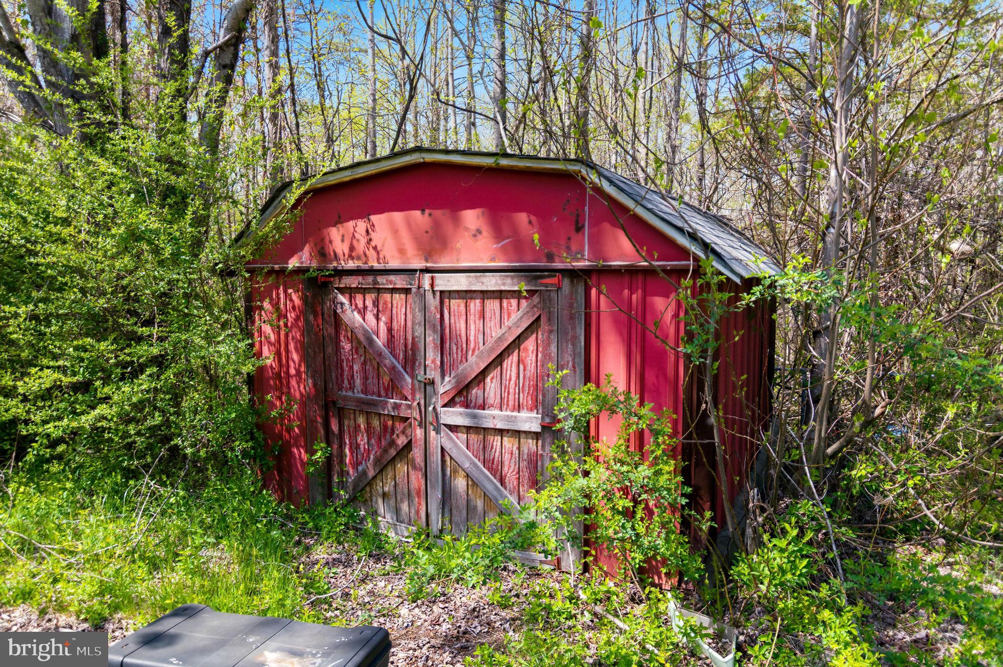 2263 Buckner Road Bumpass, VA 23024 - Photo 18 of 26 Charming red shed in lush greenery.