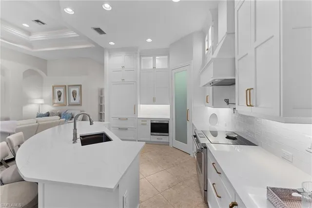 a kitchen with a sink a stove and white cabinets