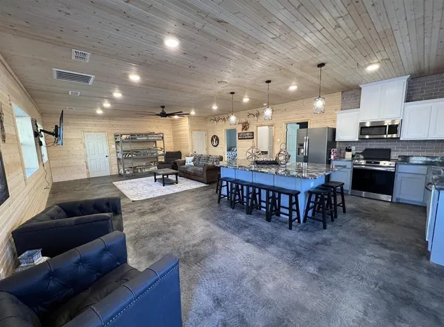 a living room with stainless steel appliances furniture a kitchen view and a kitchen counter top