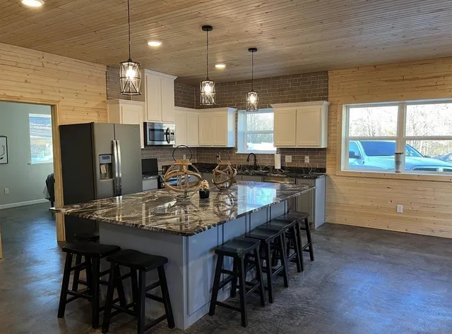 a kitchen with stainless steel appliances kitchen island granite countertop a dining table chairs and granite counter tops