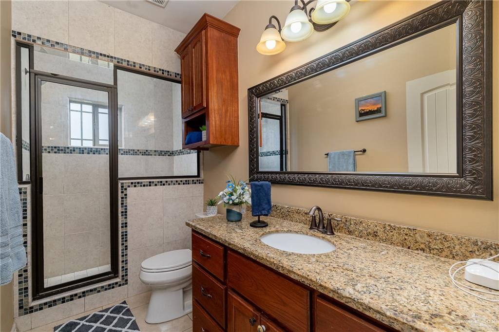 5048 Mile 8 Road Edinburg, TX 78541 - Photo 13 of 33 a bathroom with a granite countertop sink toilet and shower