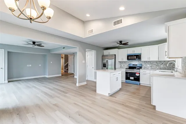 a kitchen with stainless steel appliances granite countertop a stove top oven a sink dishwasher and a refrigerator with wooden floor