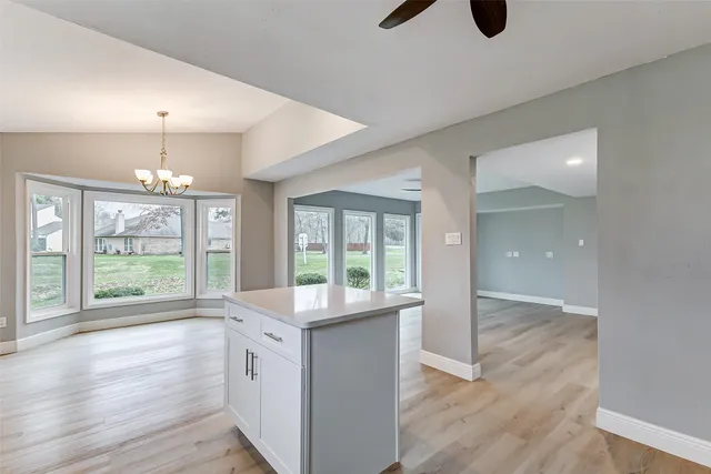 an empty room with wooden floor fireplace and windows