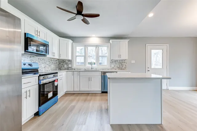 an empty room with wooden floor fireplace and windows