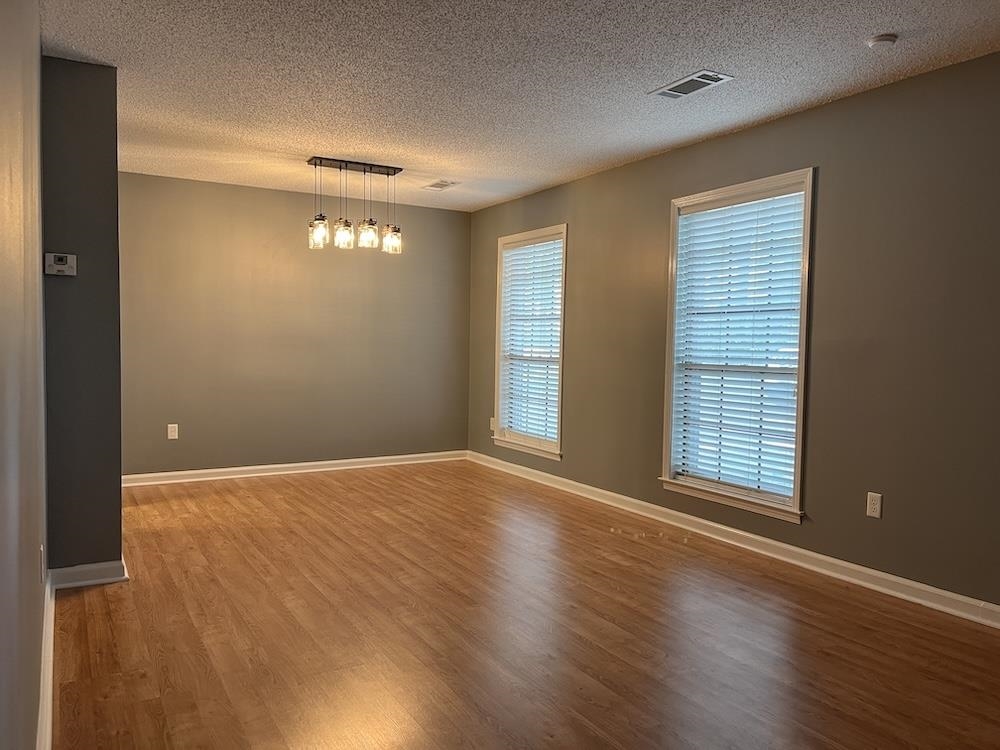 7935 Memphis Arlington Road Bartlett, TN 38133 - Photo 8 of 20 Open-concept room featuring wood-finish flooring, two windows with blinds, and a contemporary linear chandelier with five glass shades