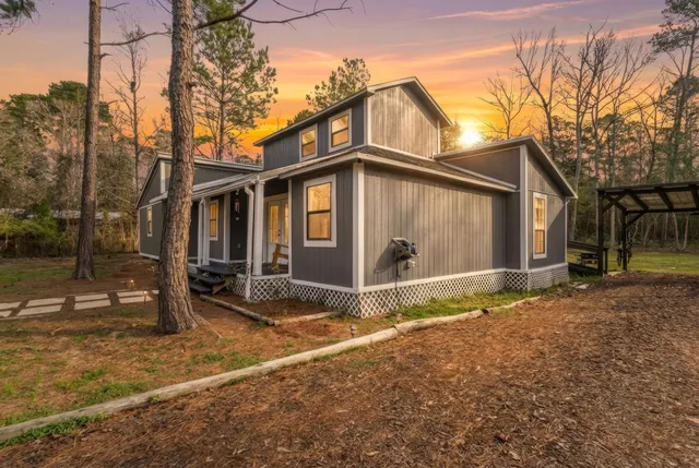 a view of a white house with large windows and a yard