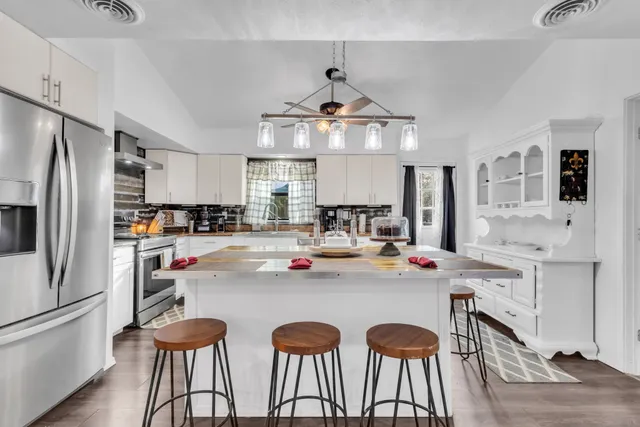 a kitchen with stainless steel appliances a table chairs refrigerator and cabinets