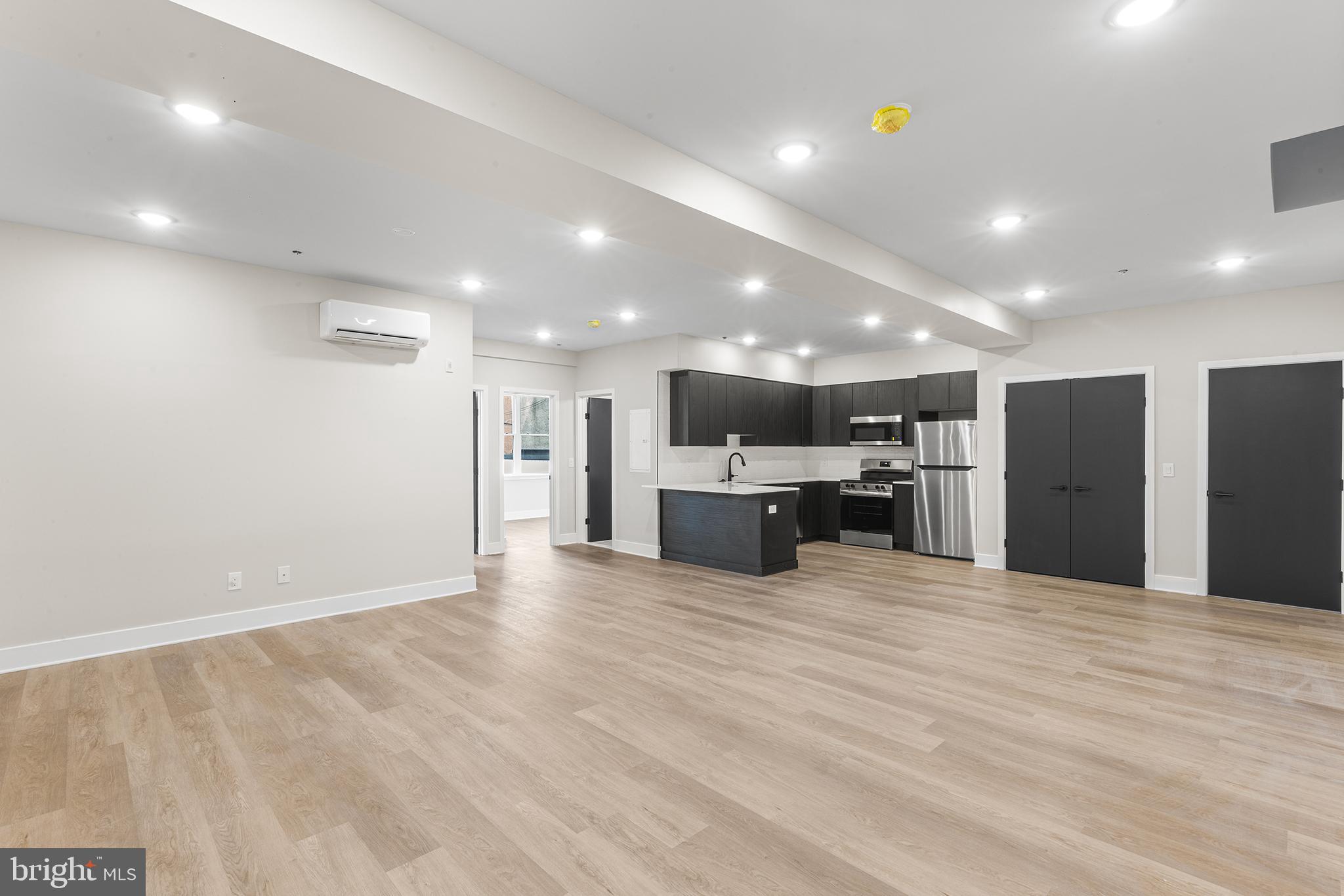a view of an empty room with kitchen view and a sink