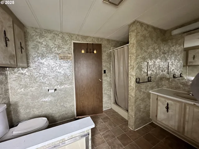 a bathroom with a granite countertop sink a toilet a mirror and shower