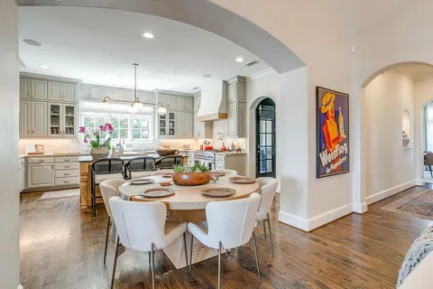 a kitchen with a table chairs cabinets and wooden floor