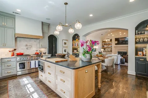 a kitchen that has a lot of white cabinets and stainless steel appliances