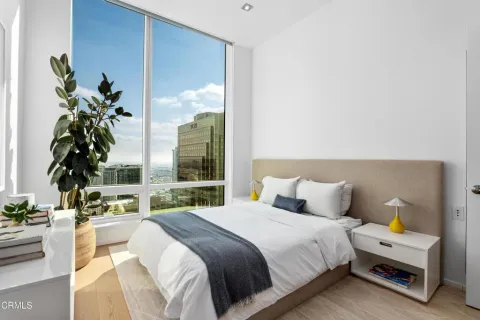 a bedroom with a bed a table and a potted plant