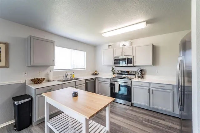 a kitchen with a sink a stove a refrigerator and black cabinets