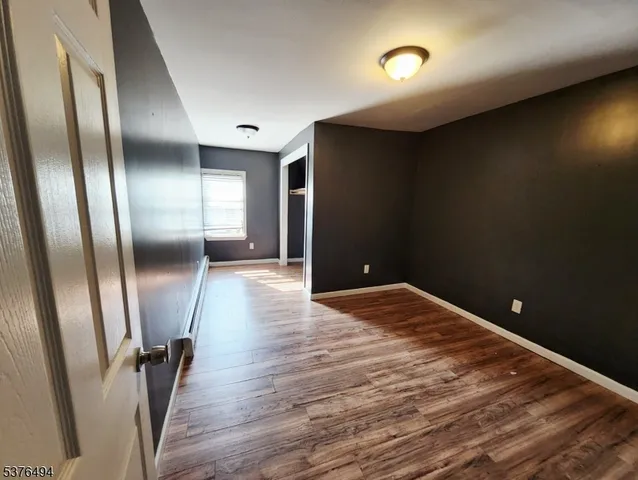 an empty room with wooden floor and a mirror