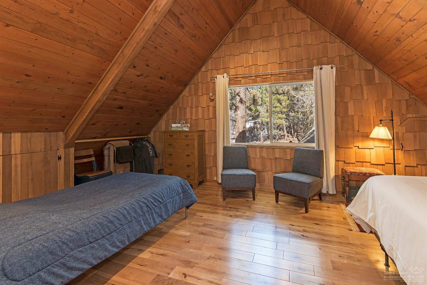 16033 Cattle Drive Road Sisters, OR 97759 - Photo 12 of 22 a bedroom with a large bed a balcony with wooden floor
