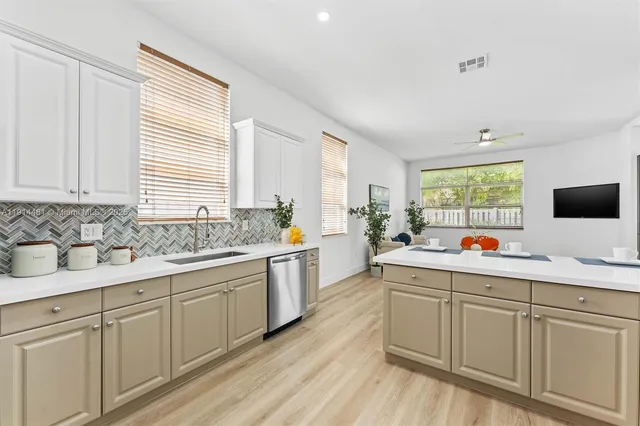 a kitchen with white cabinets and sink