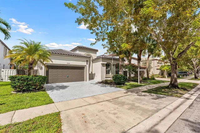 a front view of a house with a garden and trees