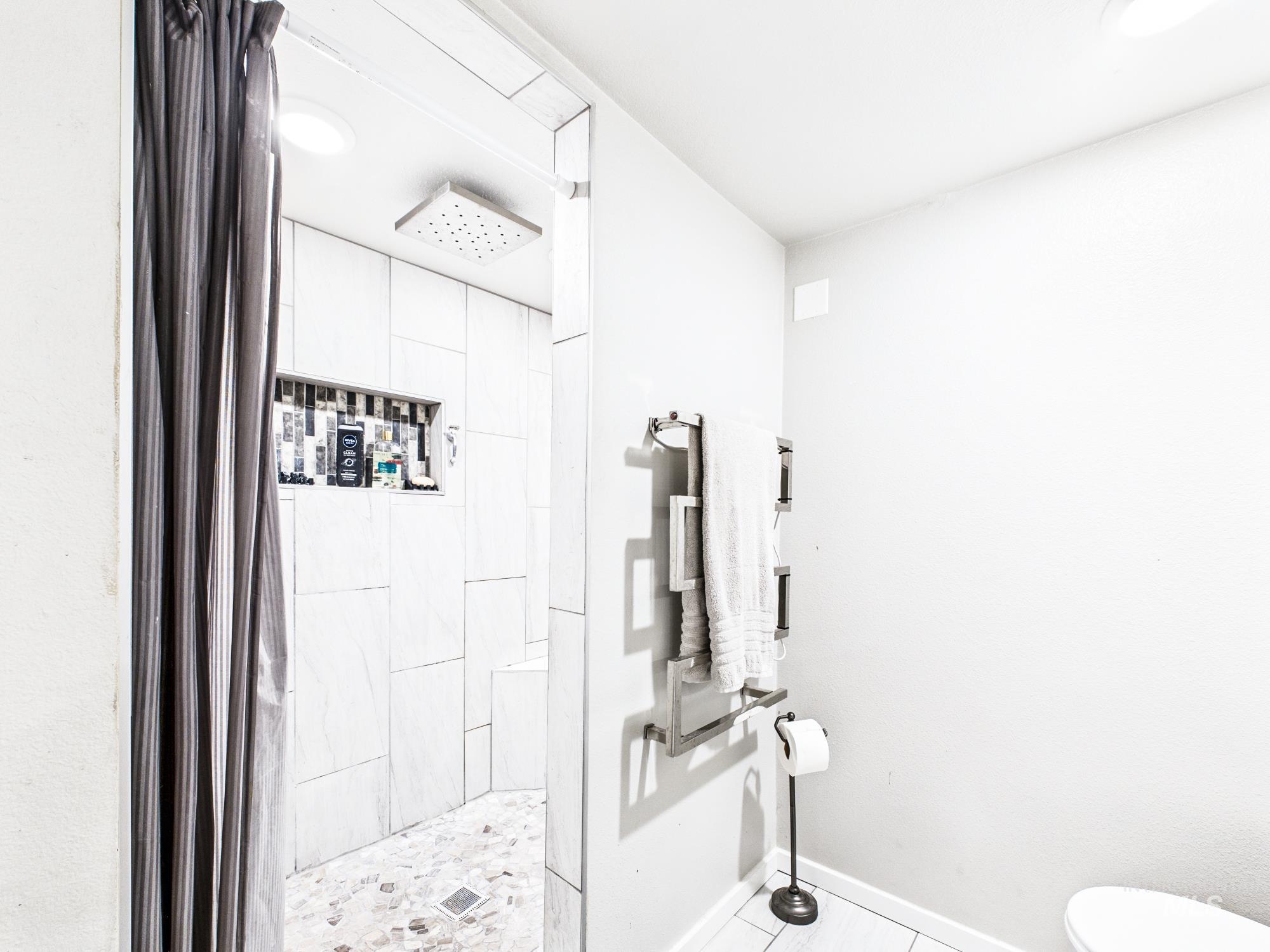 3422 6th Street Lewiston, ID 83501 - Photo 26 of 43 Walk-in shower featuring light-toned large format tile walls, a pebble-stone floor, and a recessed niche with decorative tile accents