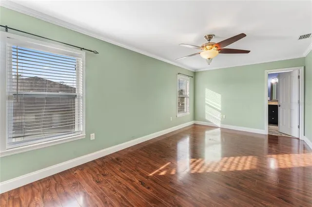 a view of empty room with wooden floor and fan