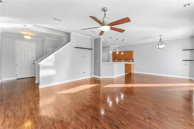 a view of a livingroom with wooden floor white ceiling fan and window