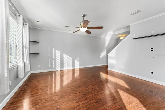 a view of an empty room with wooden floor and a window