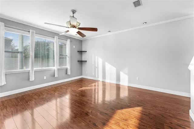 a view of an empty room with window and wooden floor