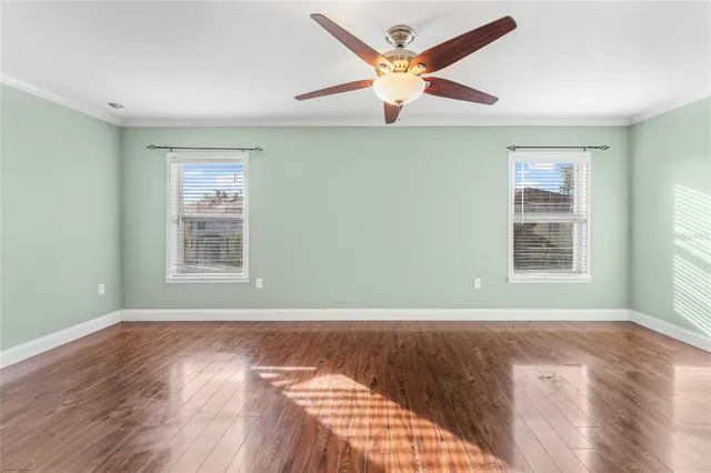 a view of an empty room with a window and wooden floor