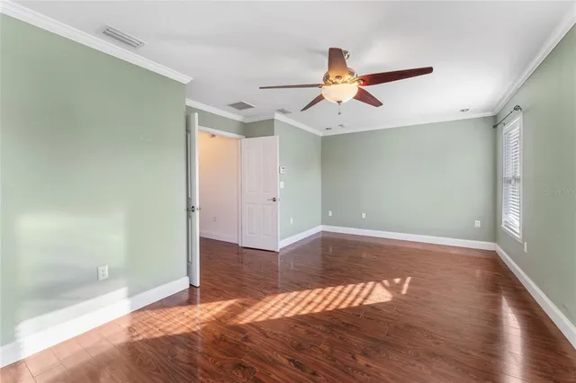 a view of empty room with wooden floor and fan