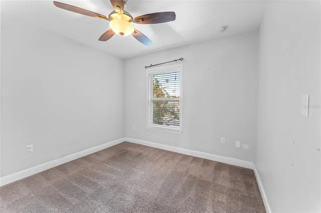 an empty room with a window and a fan