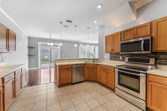 a large kitchen with stainless steel appliances granite countertop a stove top oven a sink dishwasher a dining table and chairs with wooden floor