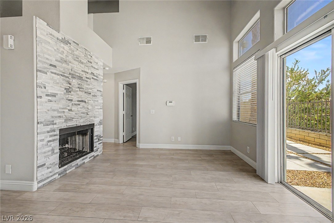 2316 Ramsgate Drive Henderson, NV 89074 - Photo 7 of 28 A spacious living area showcasing a stacked stone fireplace and tall windows for abundant light.