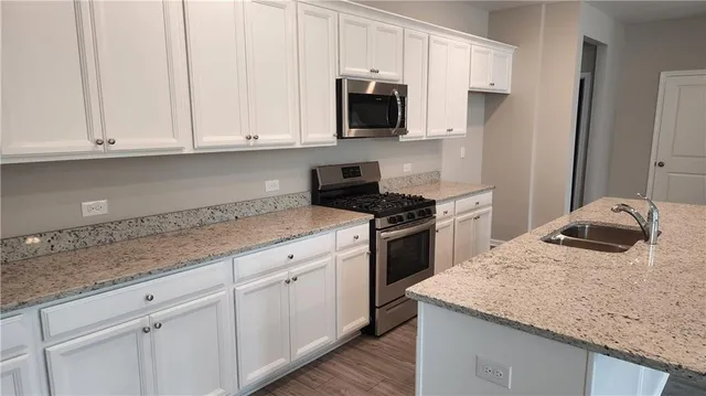 a kitchen with granite countertop white cabinets and a stove