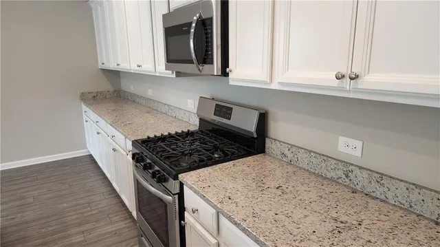 a kitchen with granite countertop a sink stove and cabinets