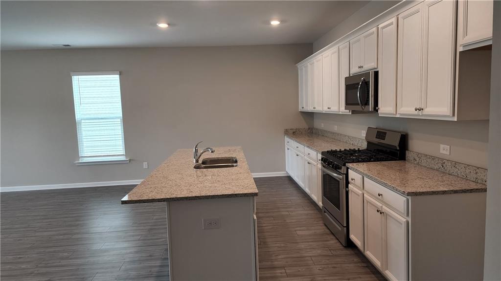 400 Grey Falcon Avenue Braselton, GA 30517 - Photo 5 of 31 a kitchen with kitchen island granite countertop a sink a stove top oven a counter space and cabinets
