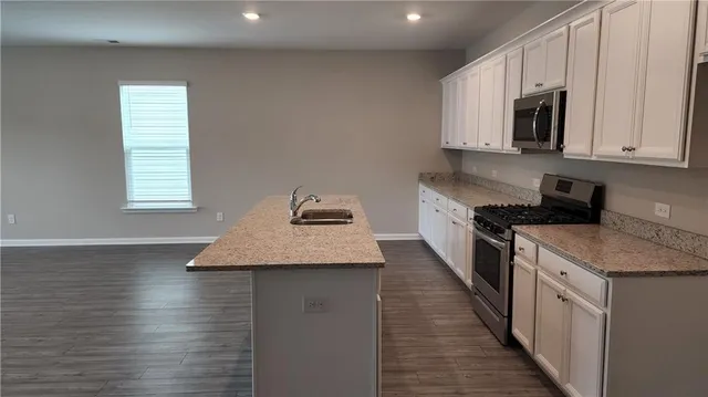 a kitchen with granite countertop kitchen island stainless steel appliances a sink stove top oven and cabinets