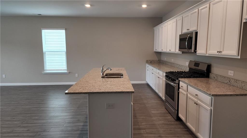 400 Grey Falcon Avenue Braselton, GA 30517 - Photo 6 of 31 a kitchen with granite countertop kitchen island stainless steel appliances a sink stove top oven and cabinets
