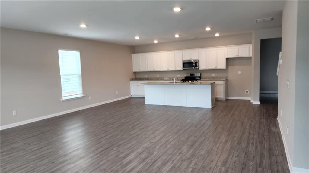 400 Grey Falcon Avenue Braselton, GA 30517 - Photo 7 of 31 a kitchen with stainless steel appliances granite countertop a sink a microwave a refrigerator and white cabinets with wooden floor