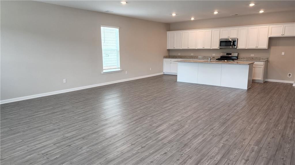 400 Grey Falcon Avenue Braselton, GA 30517 - Photo 8 of 31 a kitchen with stainless steel appliances granite countertop a sink a microwave a refrigerator and white cabinets with wooden floor