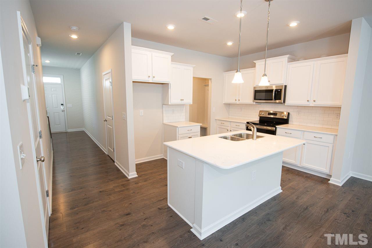 3616 Water Mist Lane, Unit 33 Raleigh, NC 27604 - Photo 5 of 26 a kitchen with kitchen island a sink a stove a refrigerator and white cabinets