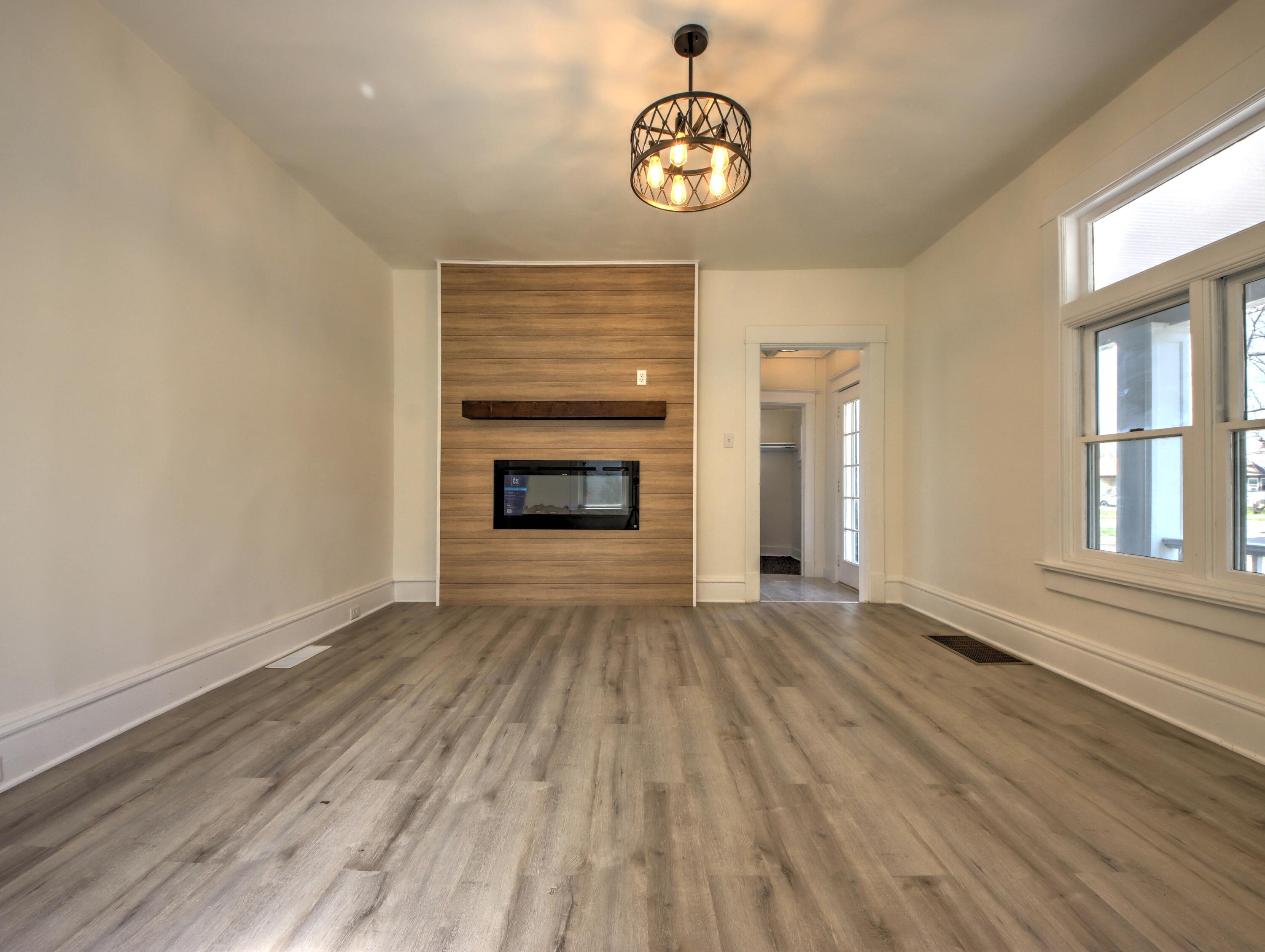 508 F Street La Porte, IN 46350 - Photo 7 of 52 an empty room with wooden floor fireplace and windows