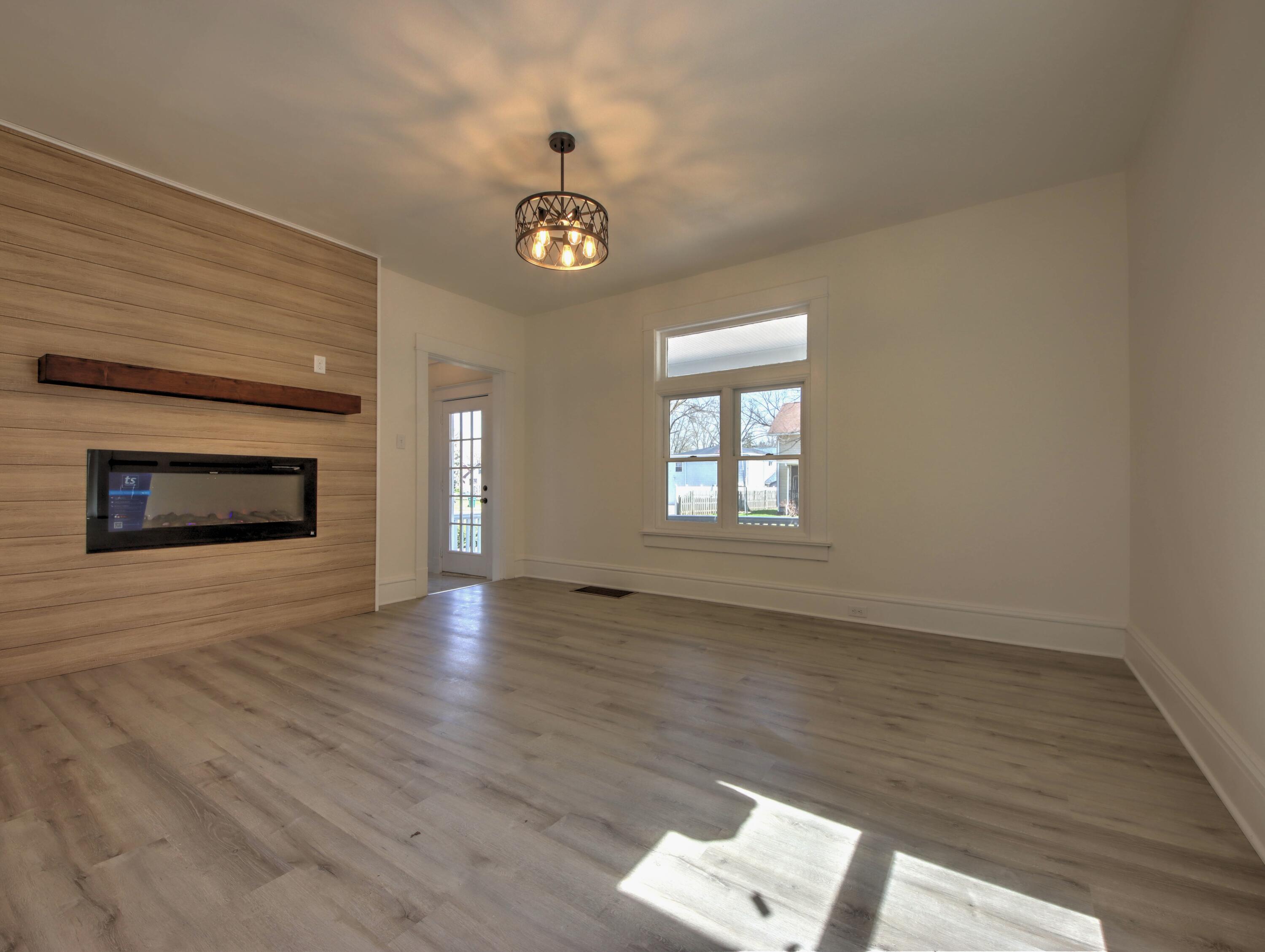 508 F Street La Porte, IN 46350 - Photo 10 of 52 an empty room with wooden floor fireplace and windows