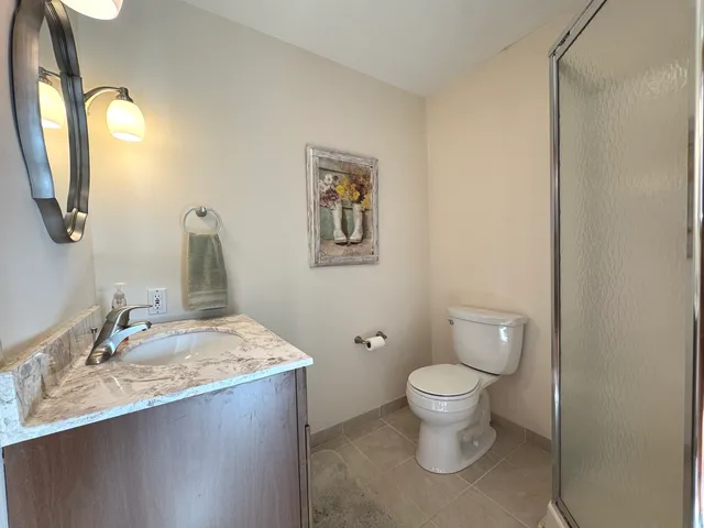 a bathroom with a granite countertop toilet a sink and a mirror