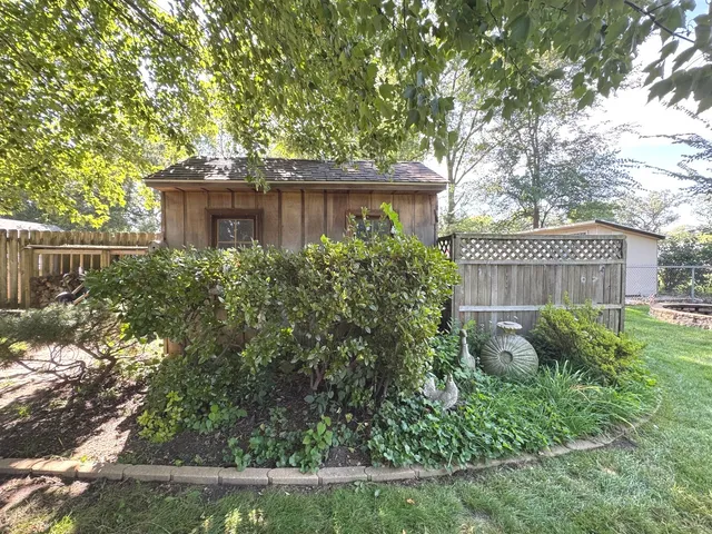 a view of a backyard with plants and large trees