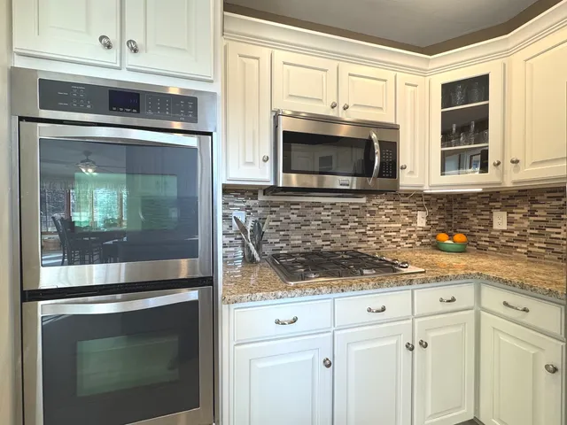 a kitchen with granite countertop white cabinets stainless steel appliances and a sink