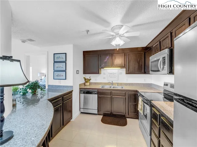 a kitchen with granite countertop a sink stove and refrigerator