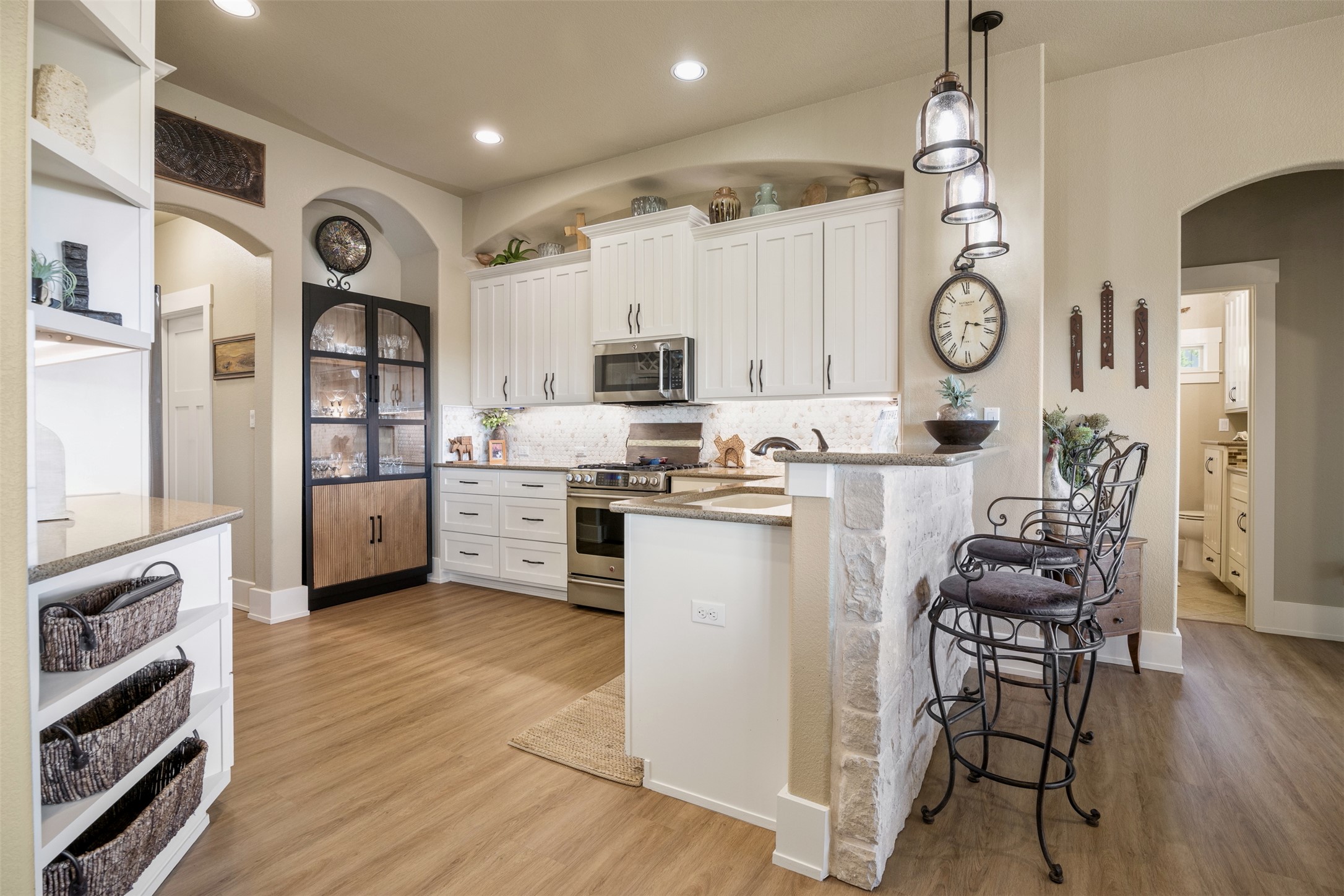 261 Barber Drive Wimberley, TX 78676 - Photo 11 of 37 Kitchen featuring arched walkways, white cabinetry, light stone counters, stainless steel appliances, and a peninsula