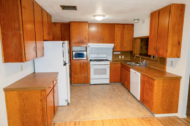 a kitchen with stainless steel appliances a refrigerator a sink a stove top oven a counter space and cabinets