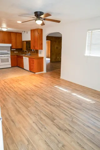 an empty room with wooden floor and kitchen view