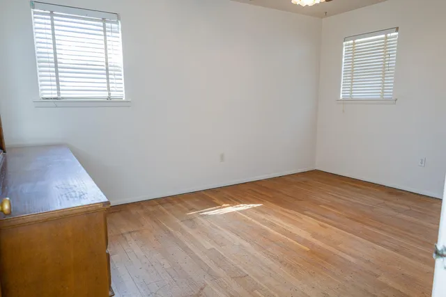an empty room with wooden floor and window